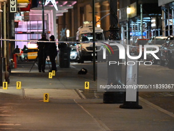 NYPD Crime Scene Unit investigators mark the crime scene where a 17-year-old boy is killed and an 18-year-old man is injured after they are...