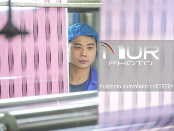 A worker produces environmentally friendly plastic bags at a workshop in Huzhou, China, on December 6, 2024. (