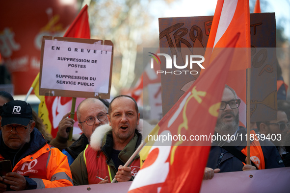 A placard reads 'On strike, jobs cut: public services removal'. Between 8,000 and 10,000 protesters march in Toulouse, France, on December 5...