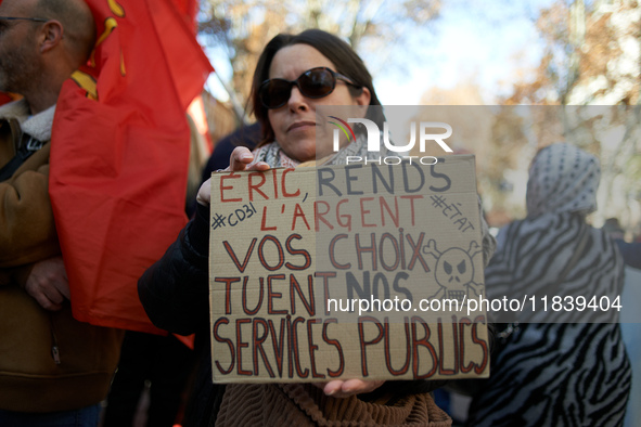 A woman holds a placard reading 'Give us back the money, your choices are killing our public services'. Between 8,000 and 10,000 protesters...