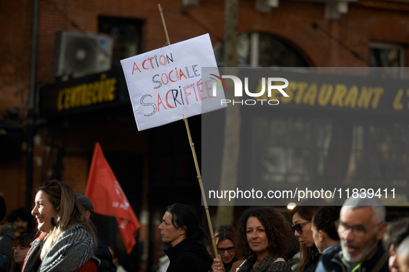 A woman holds a placard reading 'Social action sacrificed'. Between 8,000 and 10,000 protesters march in Toulouse, France, on December 5, 20...