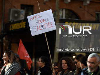 A woman holds a placard reading 'Social action sacrificed'. Between 8,000 and 10,000 protesters march in Toulouse, France, on December 5, 20...