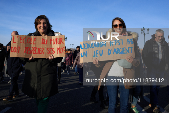 Two women hold placards reading 'The school of the future must respect its teachers' (L) and 'Education isn't a money game' (R). Between 8,0...