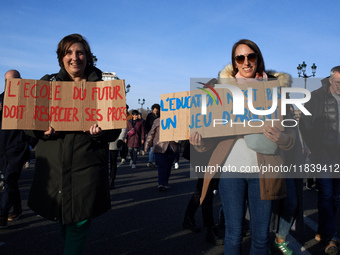 Two women hold placards reading 'The school of the future must respect its teachers' (L) and 'Education isn't a money game' (R). Between 8,0...