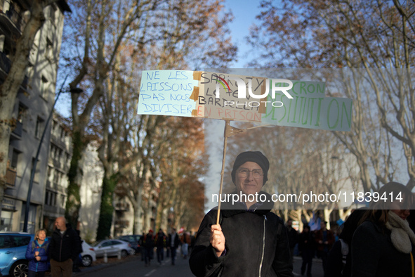 A woman holds a placard reading 'Don't let them divide us, Sarkozy, Le Pen, Bardella in jail, destitution of Macron'. Between 8,000 and 10,0...