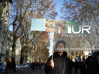 A woman holds a placard reading 'Don't let them divide us, Sarkozy, Le Pen, Bardella in jail, destitution of Macron'. Between 8,000 and 10,0...