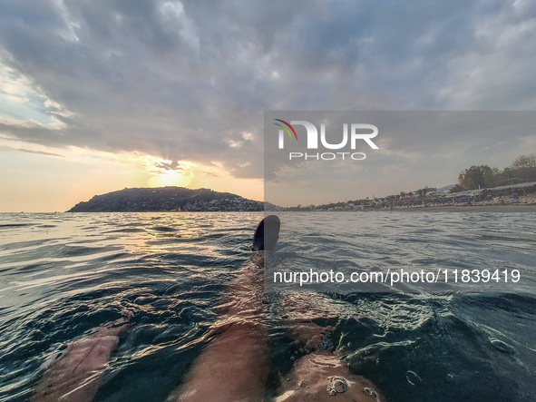 A man swims in the Mediterranean Sea while looking at Alanya Beach during a sunset in Alanya, Turkey, on November 3, 2024. 