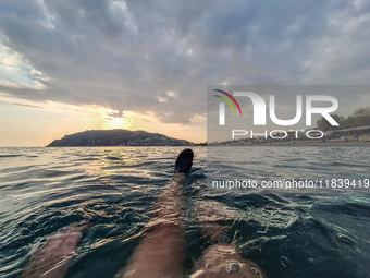 A man swims in the Mediterranean Sea while looking at Alanya Beach during a sunset in Alanya, Turkey, on November 3, 2024. (