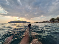 A man swims in the Mediterranean Sea while looking at Alanya Beach during a sunset in Alanya, Turkey, on November 3, 2024. (