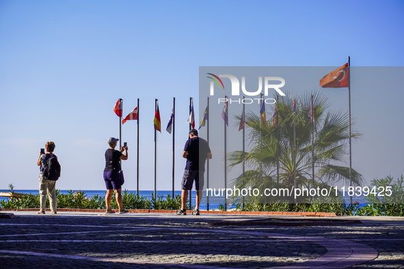 People take pictures of the Turkish flag in the wind on the Mediterranean Sea coast with their smartphones in Alanya, Turkey, on November 5,...