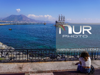 A young woman sits on a bench and looks at a tourist boat sailing in the Mediterranean Sea in Alanya, Turkey, on November 5, 2024. (