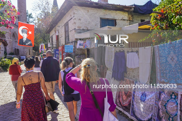 People visit a local market in Alanya, Turkey, on November 5, 2024. A portrait of Mustafa Kemal Ataturk hangs above a street. 