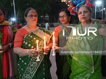 Members of a social organization hold a candlelight vigil in memory of relatives lost in the Liberation War of 1971 and those killed in the...