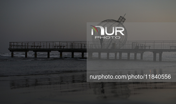 A man looks at his phone on a pier next to a giant Christmas ball in Larnaca. Cyprus, Friday, December 6, 2024 