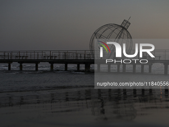 A man looks at his phone on a pier next to a giant Christmas ball in Larnaca. Cyprus, Friday, December 6, 2024 (