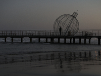 A man looks at his phone on a pier next to a giant Christmas ball in Larnaca. Cyprus, Friday, December 6, 2024 (