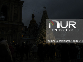 People walk around Ukraine's main Christmas tree before its lights are switched on amid Russia's attack on Ukraine in Sophia Square in Kyiv,...