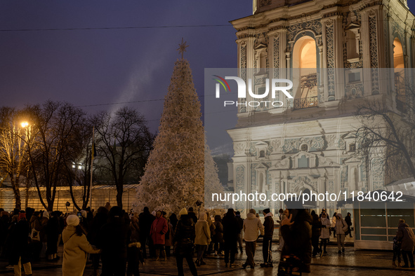 People walk around Ukraine's main Christmas tree after its lights are switched on amid Russia's attack on Ukraine in Sophia Square in Kyiv,...