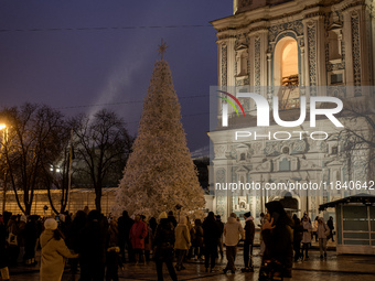 People walk around Ukraine's main Christmas tree after its lights are switched on amid Russia's attack on Ukraine in Sophia Square in Kyiv,...