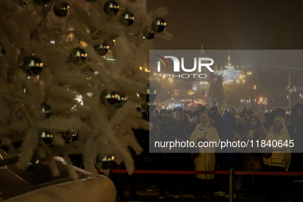 People walk around Ukraine's main Christmas tree before its lights are switched on amid Russia's attack on Ukraine in Sophia Square in Kyiv,...