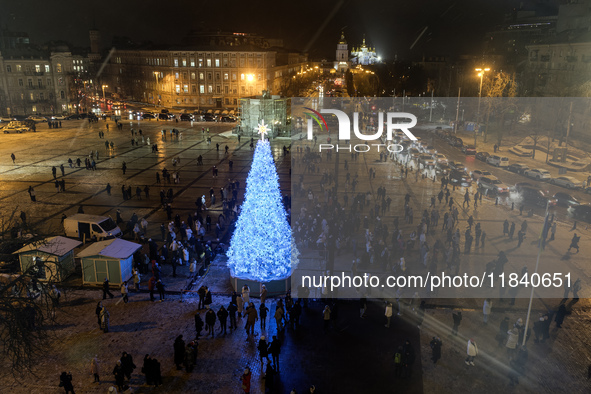 People walk around Ukraine's main Christmas tree after its lights are switched on amid Russia's attack on Ukraine in Sophia Square in Kyiv,...