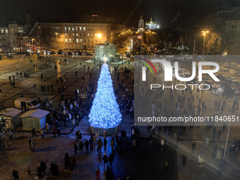 People walk around Ukraine's main Christmas tree after its lights are switched on amid Russia's attack on Ukraine in Sophia Square in Kyiv,...