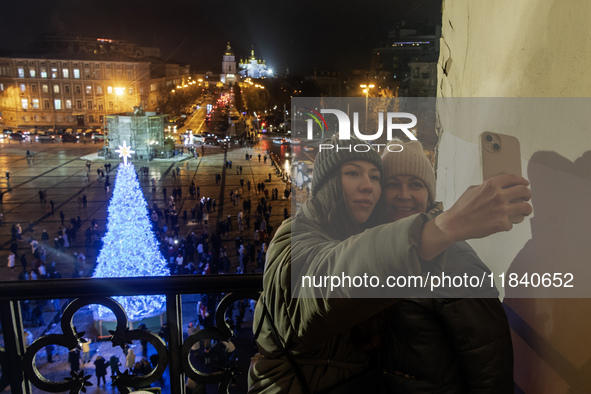 People take pictures near Ukraine's main Christmas tree after its lights are switched on amid Russia's attack on Ukraine in Sophia Square in...