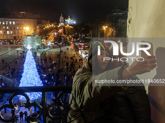 People take pictures near Ukraine's main Christmas tree after its lights are switched on amid Russia's attack on Ukraine in Sophia Square in...