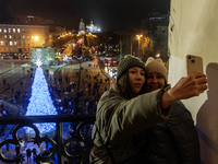 People take pictures near Ukraine's main Christmas tree after its lights are switched on amid Russia's attack on Ukraine in Sophia Square in...