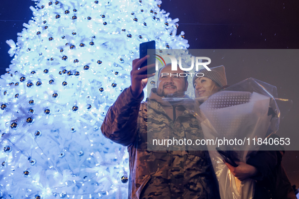 People take pictures near Ukraine's main Christmas tree after its lights are switched on amid Russia's attack on Ukraine in Sophia Square in...