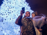 People take pictures near Ukraine's main Christmas tree after its lights are switched on amid Russia's attack on Ukraine in Sophia Square in...