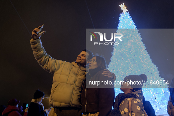 People take pictures near Ukraine's main Christmas tree after its lights are switched on amid Russia's attack on Ukraine in Sophia Square in...