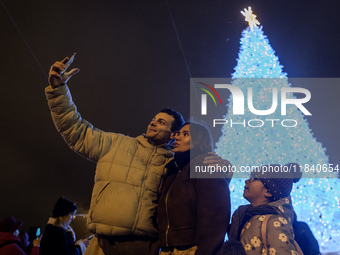 People take pictures near Ukraine's main Christmas tree after its lights are switched on amid Russia's attack on Ukraine in Sophia Square in...