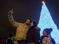 People take pictures near Ukraine's main Christmas tree after its lights are switched on amid Russia's attack on Ukraine in Sophia Square in...