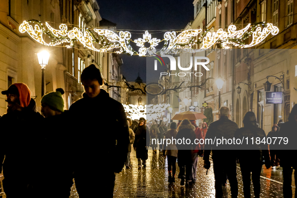 Visitors walk on landmark Florianska street near the Main Square as Christmas decorations become present in Krakow, Poland on October 6, 202...