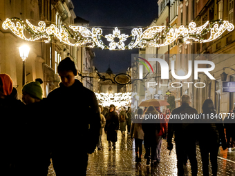 Visitors walk on landmark Florianska street near the Main Square as Christmas decorations become present in Krakow, Poland on October 6, 202...