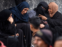 Palestinian women mourn relatives killed in an Israeli strike during their funeral at the al-Awda Hospital at the Nuseirat refugee Camp in t...