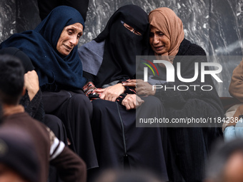 Palestinian women mourn relatives killed in an Israeli strike during their funeral at the al-Awda Hospital at the Nuseirat refugee Camp in t...