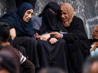 Palestinian women mourn relatives killed in an Israeli strike during their funeral at the al-Awda Hospital at the Nuseirat refugee Camp in t...