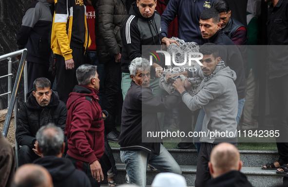 Palestinians carry a body as they prepare for a funeral at the al-Awda Hospital at the Nuseirat refugee Camp in the central Gaza Strip on De...