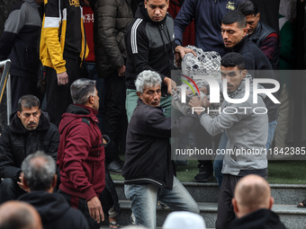 Palestinians carry a body as they prepare for a funeral at the al-Awda Hospital at the Nuseirat refugee Camp in the central Gaza Strip on De...