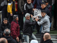 Palestinians carry a body as they prepare for a funeral at the al-Awda Hospital at the Nuseirat refugee Camp in the central Gaza Strip on De...