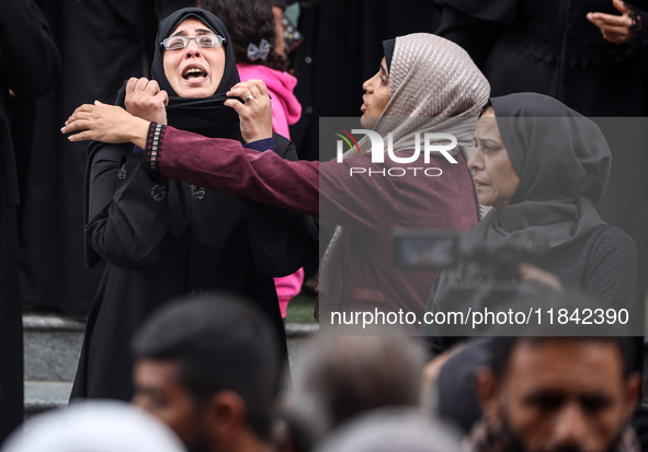 Palestinian women mourn relatives killed in an Israeli strike during their funeral at the al-Awda Hospital at the Nuseirat refugee Camp in t...