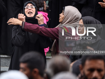 Palestinian women mourn relatives killed in an Israeli strike during their funeral at the al-Awda Hospital at the Nuseirat refugee Camp in t...