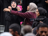 Palestinian women mourn relatives killed in an Israeli strike during their funeral at the al-Awda Hospital at the Nuseirat refugee Camp in t...