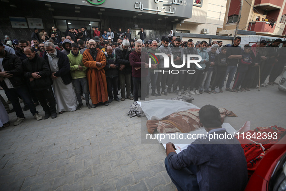 Palestinians pray by the bodies of relatives killed in Israeli strikes during a funeral at the al-Awda Hospital at the Nuseirat refugee Camp...