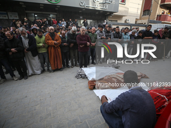 Palestinians pray by the bodies of relatives killed in Israeli strikes during a funeral at the al-Awda Hospital at the Nuseirat refugee Camp...