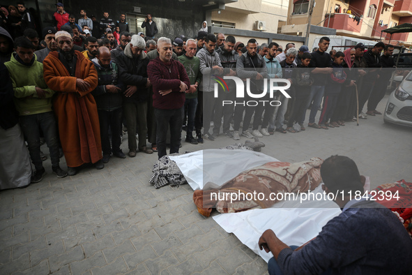 Palestinians pray by the bodies of relatives killed in Israeli strikes during a funeral at the al-Awda Hospital at the Nuseirat refugee Camp...