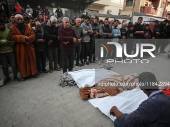 Palestinians pray by the bodies of relatives killed in Israeli strikes during a funeral at the al-Awda Hospital at the Nuseirat refugee Camp...