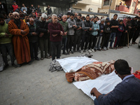 Palestinians pray by the bodies of relatives killed in Israeli strikes during a funeral at the al-Awda Hospital at the Nuseirat refugee Camp...